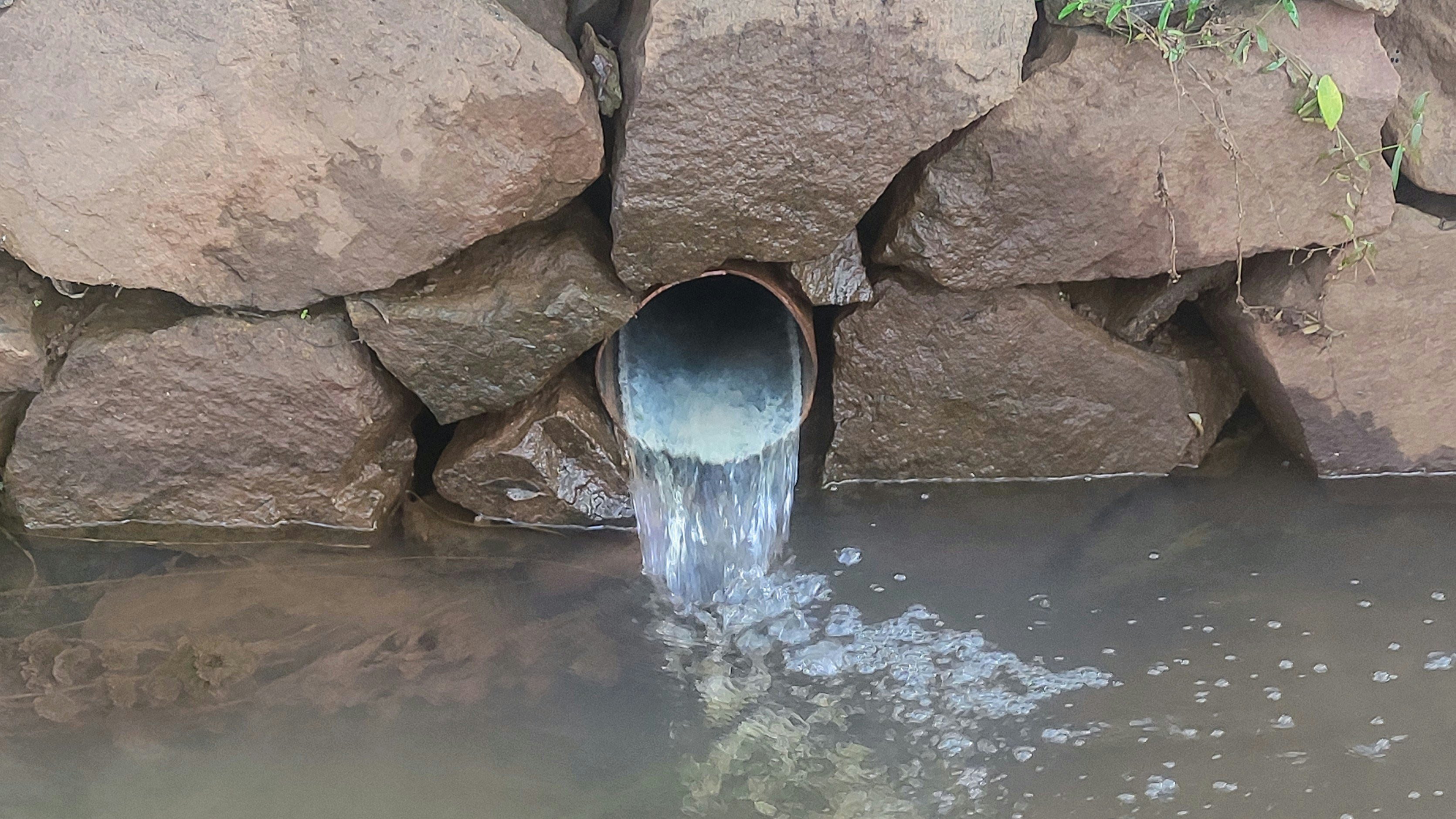 Wasser fließt aus einem Rohr in einen Kanal
